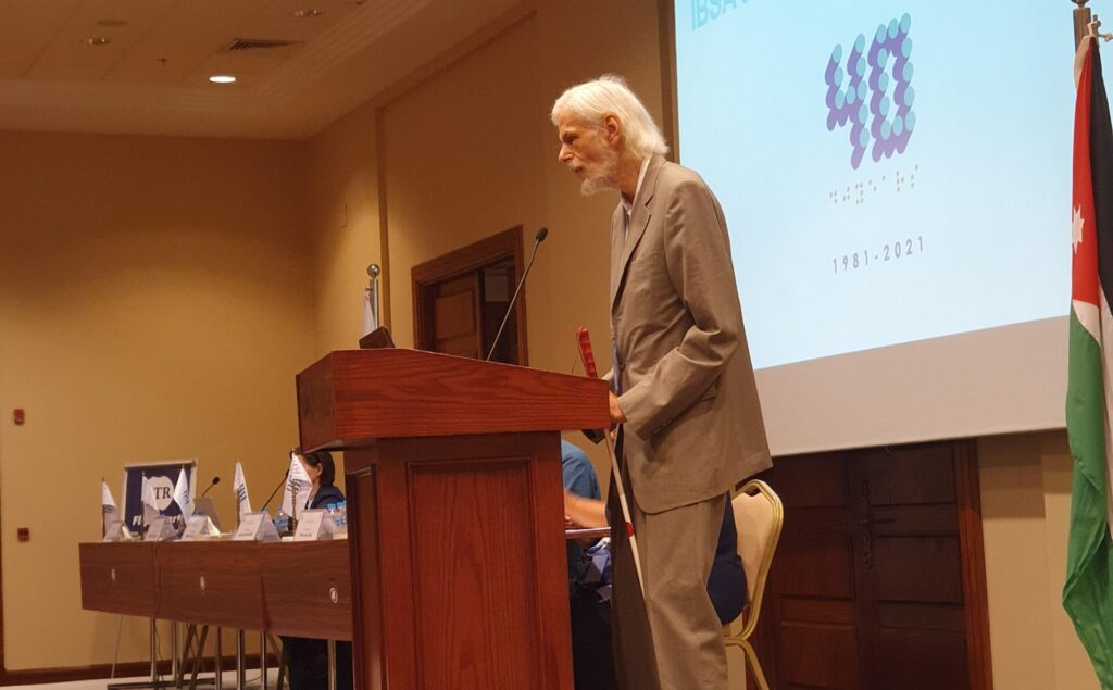 Jens Bromann of Denmark stands and speaks on the podium at the 2021 IBSA General Assembly