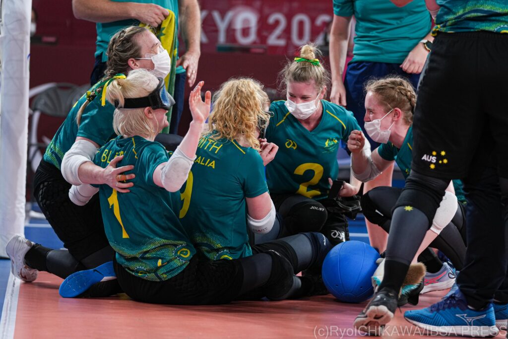 Australia sit on the goalball court and celebrate getting through to the quarter-finals